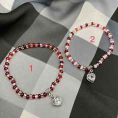 two red and white beaded bracelets sitting on top of a checkered cloth