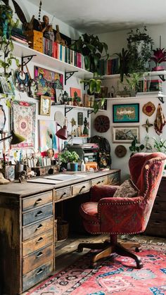 an office with lots of plants and pictures on the wall, including a red chair