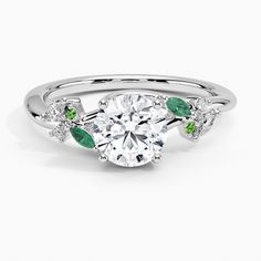 a diamond and emerald engagement ring on a white background