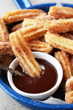 some churro sticks are in a bowl with dipping sauce