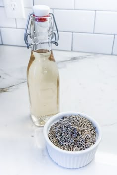 a bottle of lavender oil next to a bowl of lavender seeds