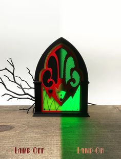 a green and red clock sitting on top of a wooden table next to a dead tree