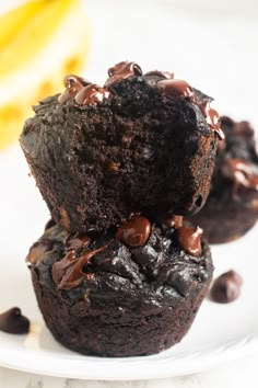 two chocolate muffins stacked on top of each other with chocolate chips around them