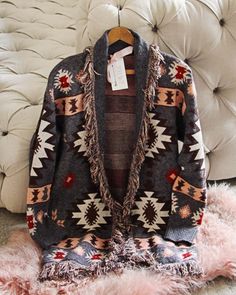 The softest knit base pairs with an Aztec print, blanket fringe & an easy long fit. Oversized long fit with an open front & soft fringe fold over collar. Color: Gray, brown, pink & red Acrylic/poly blend Hand wash cold Model is a size 8 wearing a medium. Small Medium Large Bust 40 42 44 Waist 42 44 46 Hips 44 46 48 Length 36 36 36 Bust, waist, and hip measurements are a total circumference. Length is measured from the top of the shirt to the hem. Measurements are an estimate. Native American Print Sweaters, One Size Fringe Sweater For Fall, One Size Winter Outerwear With Fringe, Oversized Fringe Sweater For Fall, Cozy Fringe Cardigan For Fall, Cozy Fringe Outerwear For Fall, Multicolor Fringe Winter Outerwear, Bohemian Soft Knit Outerwear, Bohemian Fall Outerwear For Loungewear