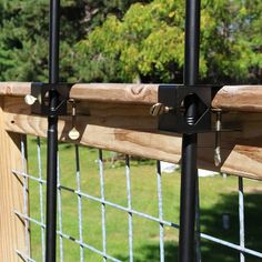 a close up of a fence with metal bars on it and wood posts in the background