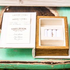 two wedding rings are in a box on a green table with an open ring box