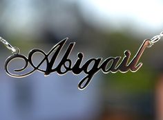 the word algarl written in cursive font on a chain with a blurry background