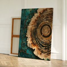 an abstract painting on the wall in a room with wood flooring and white walls