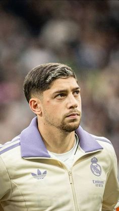 a close up of a soccer player wearing a jacket and looking off to the side