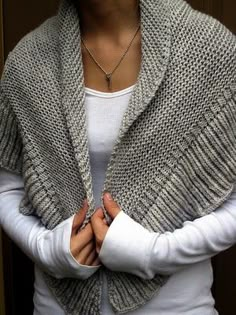 a woman standing with her arms crossed wearing a knitted shawl