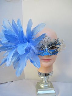 * The silver and turquoise blue mask base has been accented by scrolls of silver glitter and overlaid with a high polish silver scroll design with an outline of faceted clear crystals over the upper eye lids. On the right side an array of blue Goose feathers has been coordinated with tucks of white Maribou feathers. * To secure the mask there are blue satin ribbons used to tie in the back of the head. * Upon ordering this is the exact mask you will receive. * A great piece for a Christmas event, Blue Masquerade Mask, Silver Mask, Black Peony, Masquerade Masks, Blue Mask, Christmas Event, Back Of The Head, Peacock Color, Feather Fascinators