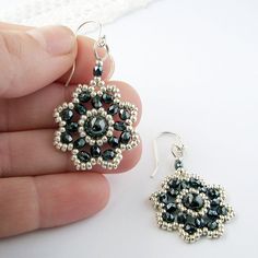 a pair of black and white beaded earrings being held by someone's hand