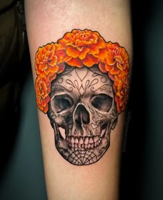 a woman's arm with a skull and flowers on it