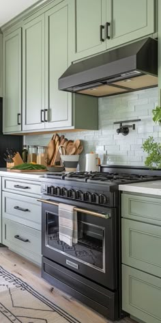 a kitchen with green cabinets and an oven in the center, surrounded by potted plants