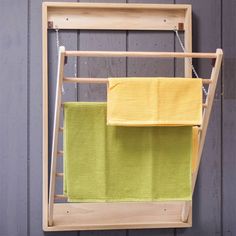 two yellow towels hanging on a wooden rack next to a gray wall with wood slats