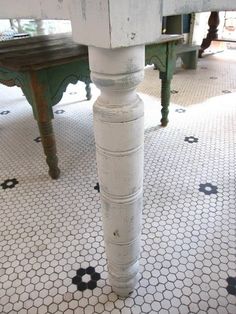 an old wooden table is painted white and has hexagonal tiles on the floor