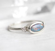 an opal and diamond ring sitting on top of a table