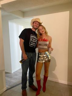 a man standing next to a woman wearing short shorts and cowboy boots in an empty room