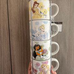 someone is holding up some coffee cups with princesses on them