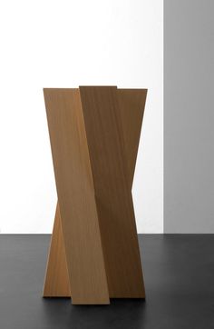 a wooden object sitting on top of a black floor next to a white and gray wall