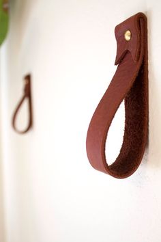 a pair of hooks mounted to the side of a white wall next to a green plant