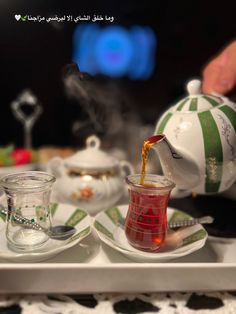 tea being poured into a glass cup on a tray