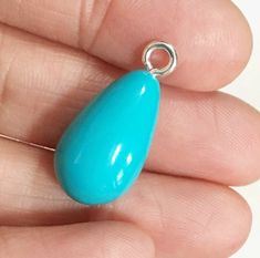 a person is holding a blue pendant in their hand