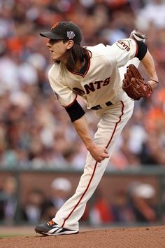 a baseball player pitching a ball on top of a field in front of an audience