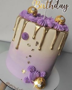 a birthday cake with purple icing and gold decorations