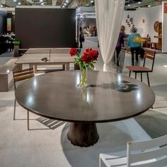 a table with flowers on it and people walking around in the background at an indoor event