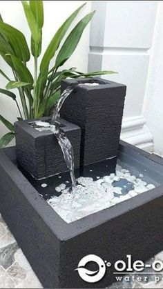 an outdoor fountain with water flowing from it's sides and plants in the background