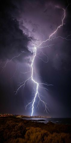 lightning strikes over the ocean at night