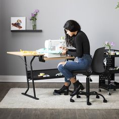 a woman sitting at a desk working on a sewing machine