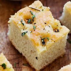 several pieces of bread on a wooden surface with herbs sprinkled all over them