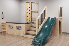 an indoor play area with a slide and climbing wall in the center, surrounded by wood flooring