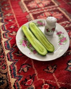 two cucumbers on a plate with a salt shaker