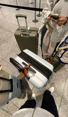 two people standing next to each other with luggage on the ground in front of them