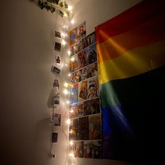 there is a rainbow flag hanging on the wall with pictures and lights strung from it