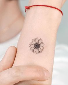 a woman's wrist tattoo with a flower on it