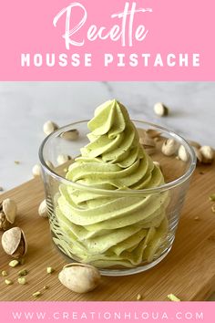 a bowl filled with green whipped cream on top of a wooden cutting board next to nuts