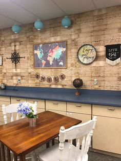 a table and chairs in a room with wood paneling on the wall behind it