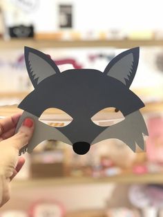 a person holding up a paper fox mask