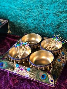 four metal bowls with toothpicks in them sitting on a purple carpeted surface