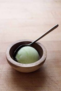 a wooden bowl filled with ice cream and a spoon in it on a wood table