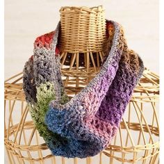 a multicolored crocheted scarf sitting on top of a wicker basket