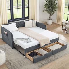 a bed with two drawers underneath it in front of a window and a rug on the floor