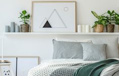 a bed with pillows and blankets on top of it next to potted greenery