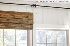 an open window with wooden blinds in front of it and a sign that says the letter cottage