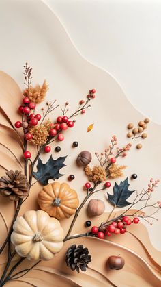 an arrangement of autumn leaves, berries and acorns on a beige background with red berries