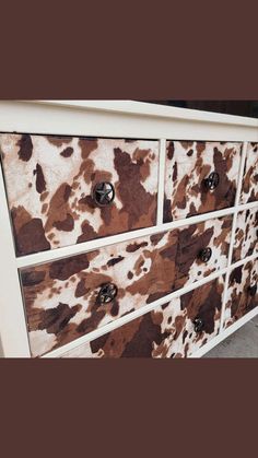 a cow print dresser with drawers and knobs